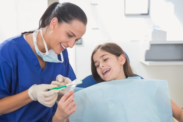 Pediatric dental assistant explaining to child
